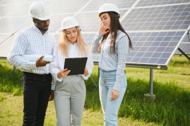 Kağıt üzerinde üç teknik mühendis planı gözden geçirip tartışıyorlar. Erkekler, kadınların nüanslarla ilgili açıklamalarını dinler..