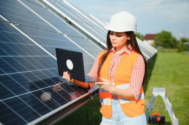 Güneş fotovoltaik panelleri kuran kadın mühendis, alternatif enerji kavramı.