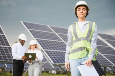 Group of investors together with young lady ecological engineer they analysing the plan of work and the efficient operation of solar batteries.
