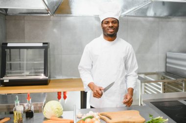 Restoranın mutfağında duran mutlu Afrika kökenli Amerikalı erkek şefin portresi..