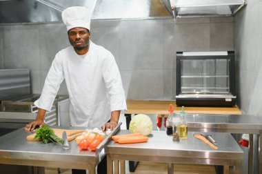 Afro-Amerikan şef restoran mutfağında kameraya bakıyor..
