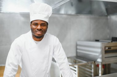 Afro-Amerikan şef restoran mutfağında kameraya bakıyor..