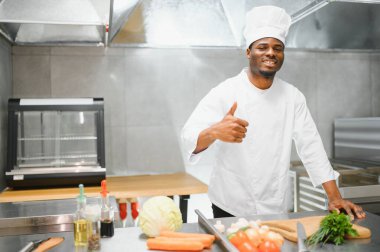 African American male chef standing at kitchen counter in restaurant kitchen, copy space.