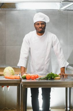 Deneyimli Afro-Amerikan şef restoranın mutfağında çalışan personelle duruyor..