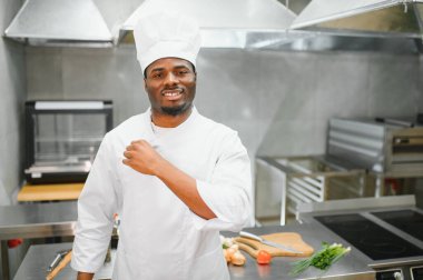 Restoranın mutfağında duran mutlu Afrika kökenli Amerikalı erkek şefin portresi..