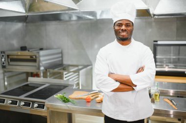 Afro-Amerikan şef restoran mutfağında kameraya bakıyor..