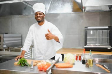 Afro-Amerikan şef restoran mutfağında kameraya bakıyor..