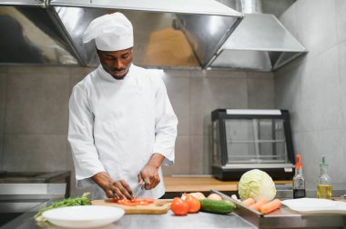 Deneyimli Afro-Amerikan şef restoranın mutfağında çalışan personelle duruyor..