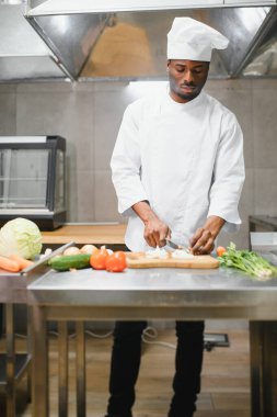 Deneyimli Afro-Amerikan şef restoranın mutfağında çalışan personelle duruyor..