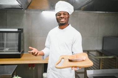 Afro-Amerikalı erkek şef restoran mutfağında somon balığı hazırlıyor..