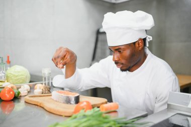 African American male chef standing at kitchen counter in restaurant kitchen, copy space.