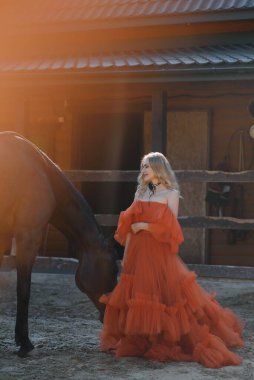Güzel model kız uzun bir elbise içinde bir atla duruyor..
