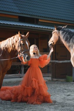 Güzel model kız uzun bir elbise içinde bir atla duruyor..