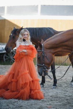 Güzel model kız uzun bir elbise içinde bir atla duruyor..