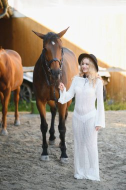 Güzel model kız uzun bir elbise içinde bir atla duruyor..