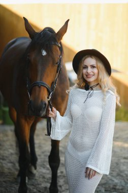 Güzel model kız uzun bir elbise içinde bir atla duruyor..