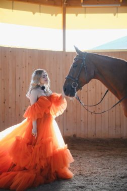 Güzel model kız uzun bir elbise içinde bir atla duruyor..