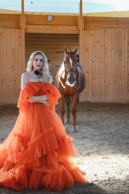 Güzel model kız uzun bir elbise içinde bir atla duruyor..