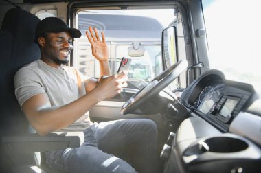 Bir kamyonun kabinindeki Afrikalı sürücü telefonla konuşuyor..