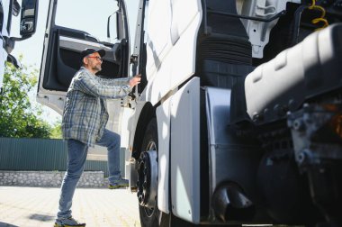 Kamyon şoförü yarı kamyonun taksisine biniyor..