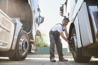 Yarı kamyon tekerleği bakım. Beyaz kamyonu makinist kamyon Servis Merkezi tekerlek göz alarak elinde büyük anahtar ile.