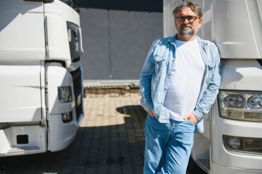 Kamyonetinin önünde duran kendinden emin mutlu erkek sürücü..