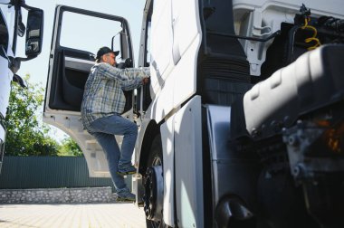 Kamyon şoförü yarı kamyonun taksisine biniyor..