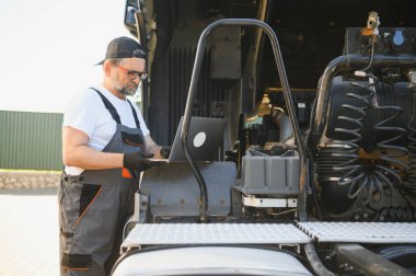 Tecrübeli oto tamircisi müşteri arabası bilgisayar kontrolü yapıyor..