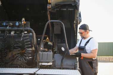 Tecrübeli oto tamircisi müşteri arabası bilgisayar kontrolü yapıyor..