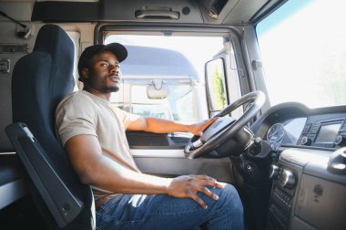 Profesyonel Afro-Amerikan kamyon şoförü günlük giysiler içinde kamyon şoförü uzun bir ulaşım yoluna gidiyor..