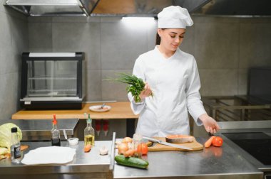 Female chef having fun while preparing food in the kitchen at restaurant.