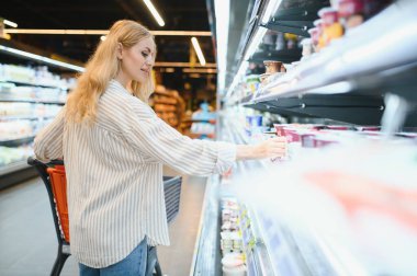Süpermarkette alışveriş arabasıyla gülümseyen kadının portresi.