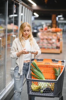 Young woman shopper in the grocery store choosing fresh chicken eggs.