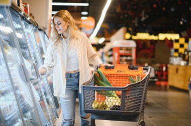 onun en sevdiği donmuş yiyecek arayan dondurucu önünde bir süpermarket duran kadın.