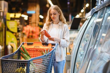 onun en sevdiği donmuş yiyecek arayan dondurucu önünde bir süpermarket duran kadın.