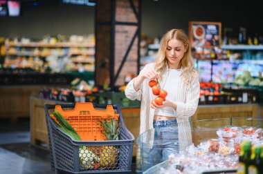 Yiyecek dükkanında ya da süpermarkette domates seçen bir kız..