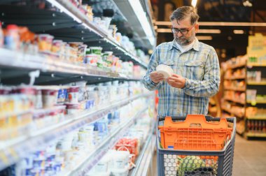 Yakışıklı adam bir süpermarkette alışveriş.