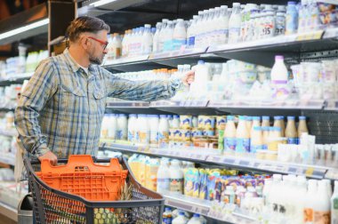 Yaşlı adam market alışverişinde ürünleri seçiyor süpermarketten yiyecek alıyor..