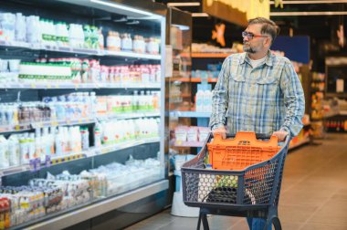 Yakışıklı adam bir süpermarkette alışveriş.