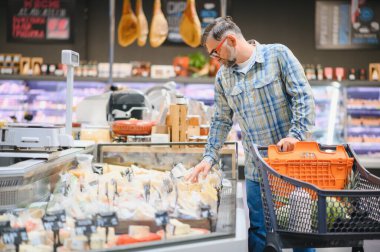 Markette alışveriş arabasını iten olgun bir adam market alışverişi, market alışverişi konsepti satın alıyor..