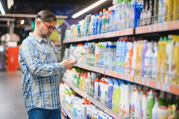 Человек в супермаркете в отделе бытовой химии. Большой выбор продукции.