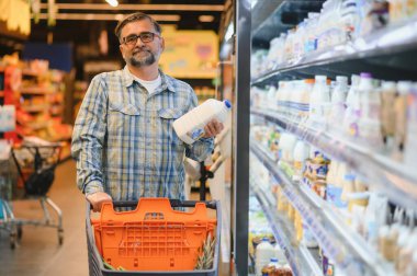 Markette alışveriş arabasını iten olgun bir adam market alışverişi, market alışverişi konsepti satın alıyor..