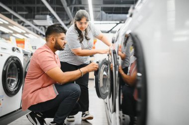 Hintli çift elektronik mağazasından çamaşır makinesini seçiyor.