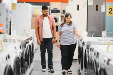 Hintli çift elektronik mağazasından çamaşır makinesini seçiyor.