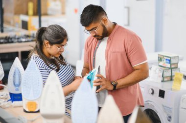 Elektronik mağazasında dikilen çift ütü yapmak için elektrikli ütü seçiyor. Ev işleri..