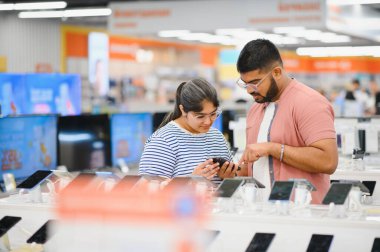 Teknolojik alışveriş aleti konsepti. Mobil dükkanından yeni bir akıllı telefon alan mutlu gençler.