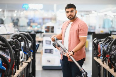Hintli bir adam elektronik mağazasından yeni bir elektrikli süpürge seçiyor..