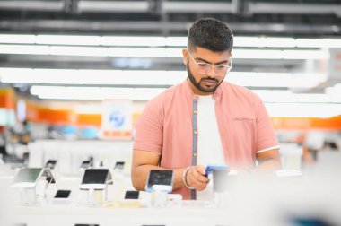 Elektronik mağazasındaki adam cep telefonunu seçiyor..