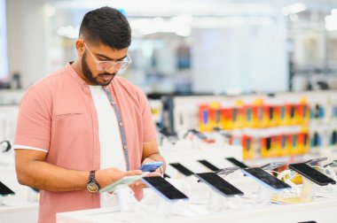 Elektronik mağazasındaki adam cep telefonunu seçiyor..