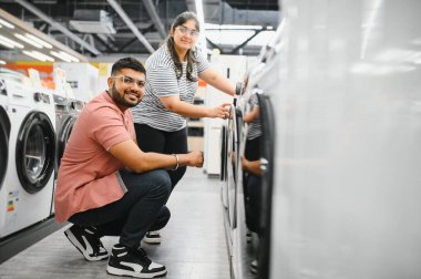 Hintli çift elektronik mağazasından çamaşır makinesini seçiyor.